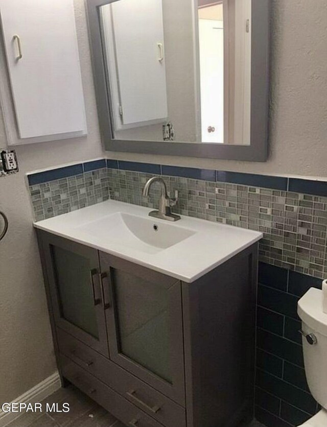 bathroom featuring vanity, tile walls, and toilet