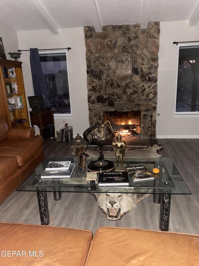 living area with beamed ceiling, wood finished floors, and a fireplace