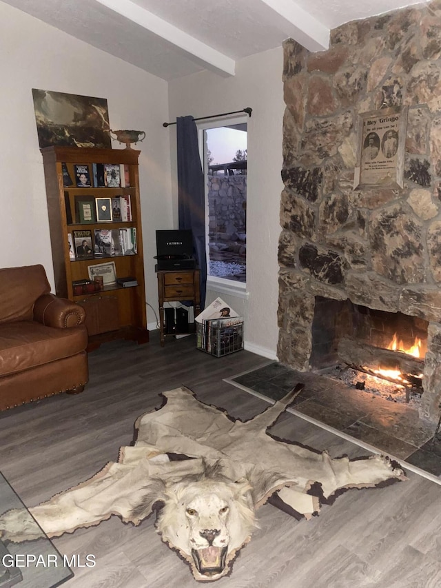 living area featuring a fireplace, lofted ceiling with beams, and wood finished floors