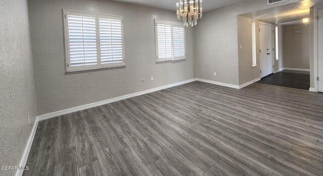 unfurnished room with baseboards, dark wood finished floors, and a textured wall