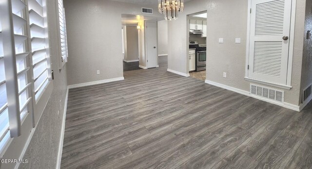 interior space featuring visible vents, baseboards, dark wood-type flooring, and a notable chandelier