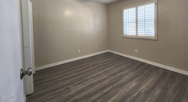 unfurnished room with dark wood-style floors, baseboards, and a textured wall