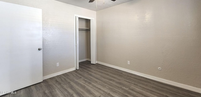 unfurnished bedroom featuring dark wood-type flooring, a ceiling fan, a closet, baseboards, and a textured wall