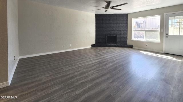 unfurnished living room featuring dark wood-type flooring, ceiling fan, baseboards, a fireplace, and a textured wall