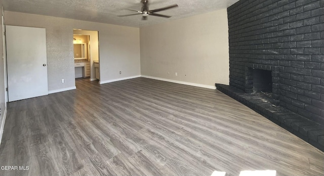 unfurnished living room featuring baseboards, a textured ceiling, a fireplace, and dark wood-style flooring