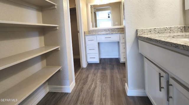 bathroom featuring baseboards, vanity, a textured wall, and wood finished floors