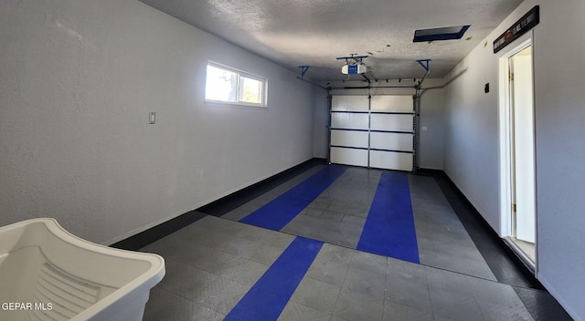 garage featuring a garage door opener, baseboards, and a textured wall