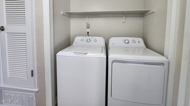 laundry room featuring laundry area, a textured wall, and separate washer and dryer