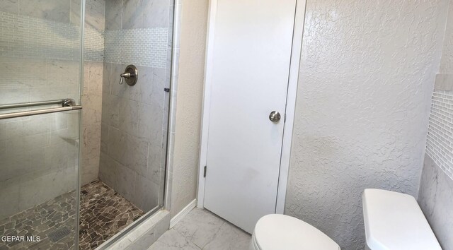 bathroom featuring a shower stall, toilet, a textured wall, and marble finish floor