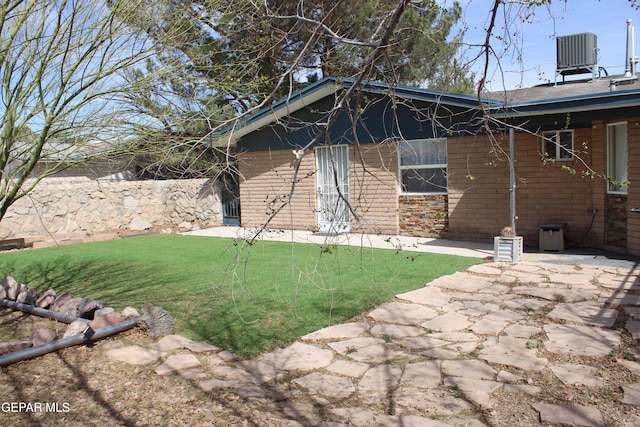 exterior space with central AC unit, a lawn, and fence