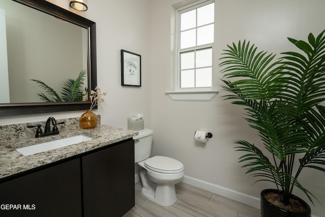 bathroom with vanity, toilet, and baseboards