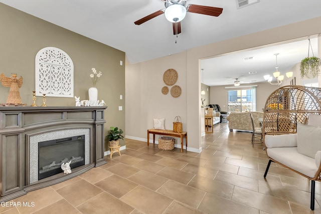 tiled living room featuring ceiling fan with notable chandelier, a tiled fireplace, visible vents, and baseboards