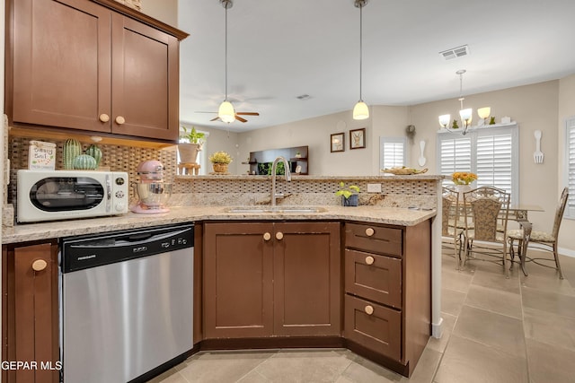 kitchen with decorative backsplash, white microwave, a peninsula, stainless steel dishwasher, and a sink