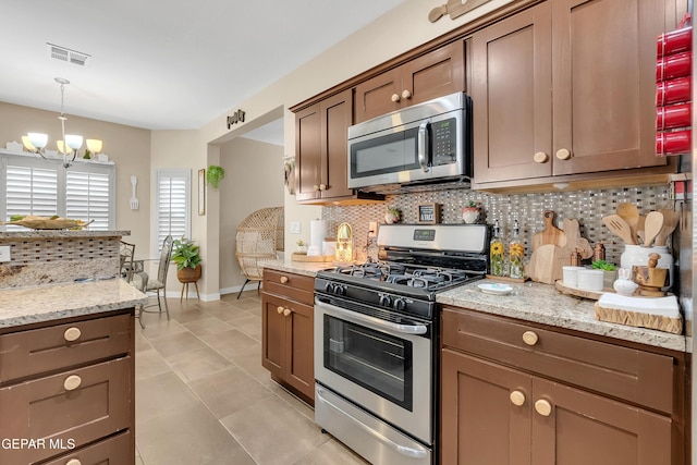 kitchen featuring visible vents, light stone countertops, an inviting chandelier, stainless steel appliances, and backsplash