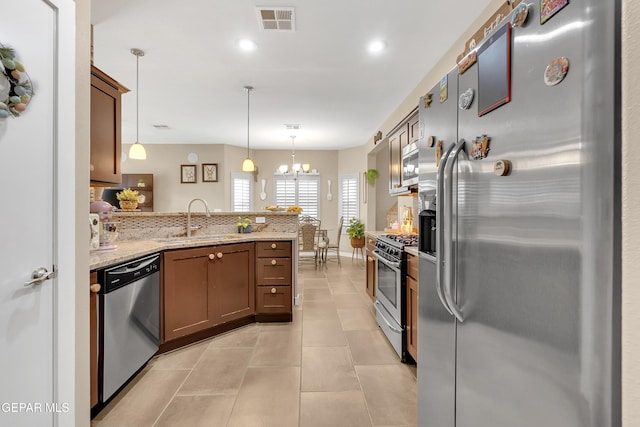 kitchen featuring light tile patterned floors, visible vents, a peninsula, stainless steel appliances, and a sink