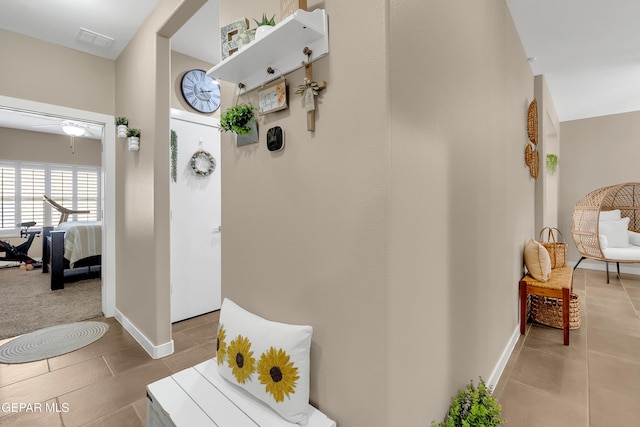 corridor with baseboards, visible vents, and tile patterned floors