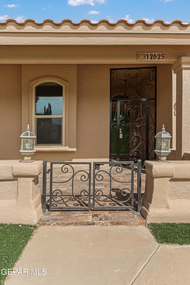 property entrance featuring a porch and a gate