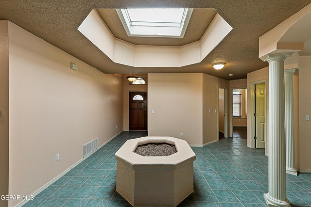 foyer entrance with dark tile patterned floors, baseboards, visible vents, and ornate columns