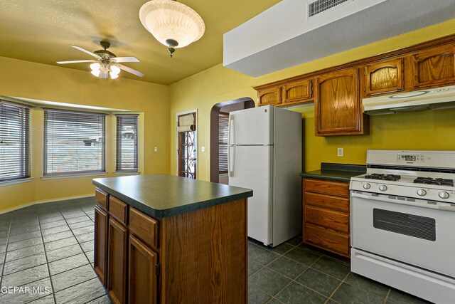 kitchen featuring white appliances, visible vents, arched walkways, under cabinet range hood, and dark countertops