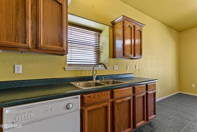 kitchen featuring dishwasher, dark countertops, baseboards, and a sink