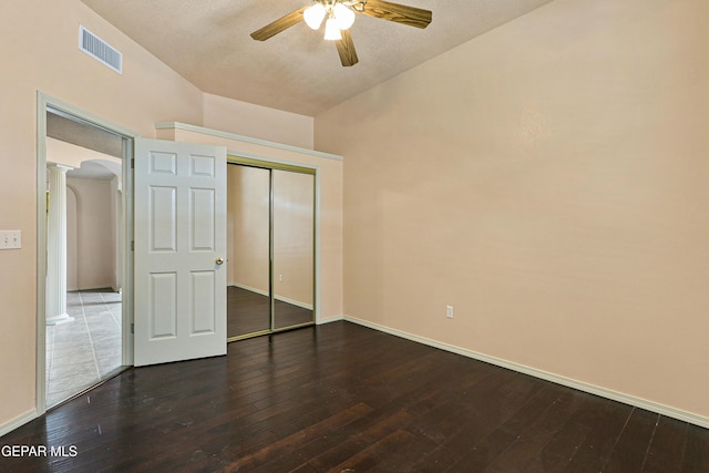 unfurnished bedroom featuring visible vents, decorative columns, arched walkways, hardwood / wood-style flooring, and a closet