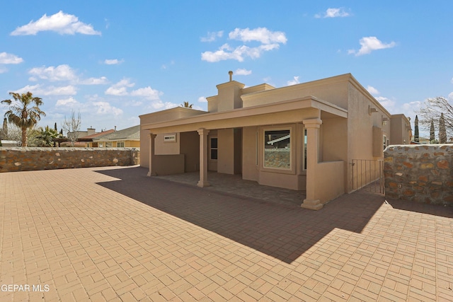 rear view of property featuring a patio area, fence, and stucco siding