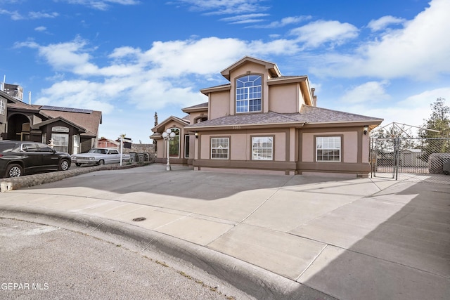 view of front of property with stucco siding, roof with shingles, and fence