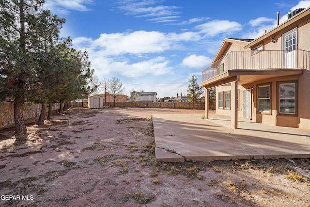 view of yard with an outdoor structure, a storage unit, a patio area, and a fenced backyard