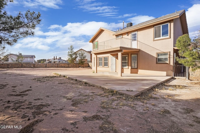 rear view of property featuring stucco siding, fence, a balcony, and a patio area