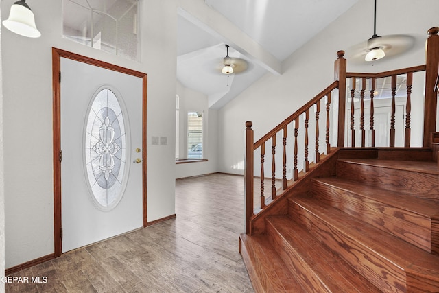 foyer with a ceiling fan, lofted ceiling with beams, wood finished floors, baseboards, and stairs