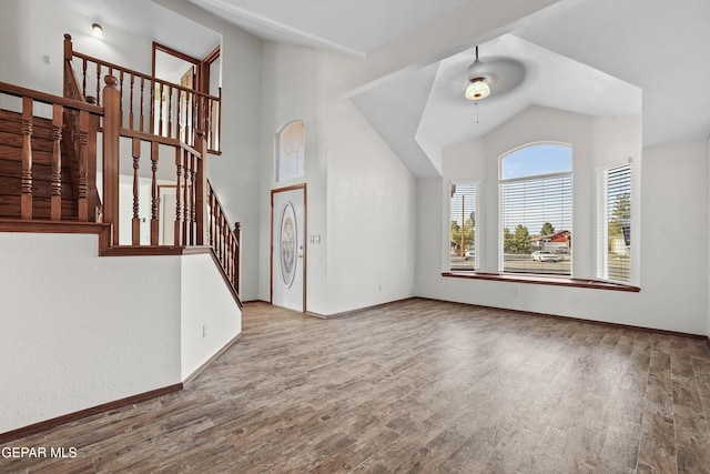 interior space featuring lofted ceiling, a ceiling fan, wood finished floors, baseboards, and stairs