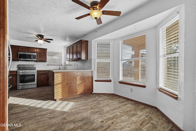 kitchen featuring dark wood-style flooring, stainless steel appliances, light countertops, a textured ceiling, and tasteful backsplash