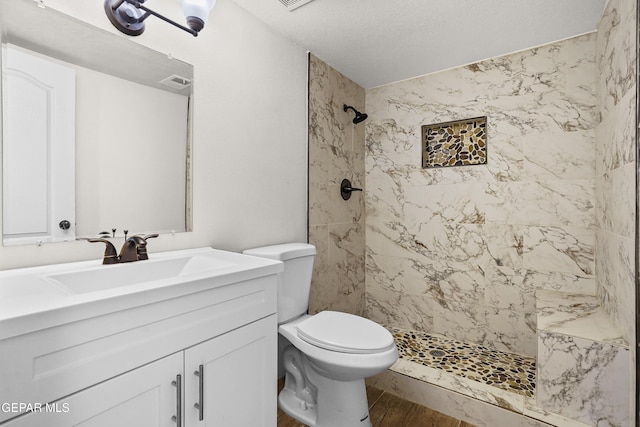 bathroom with visible vents, toilet, wood finished floors, a shower stall, and vanity