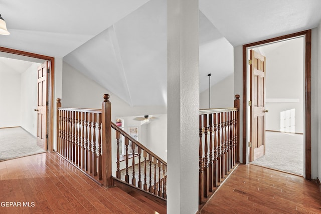 hall featuring an upstairs landing, lofted ceiling, and wood-type flooring