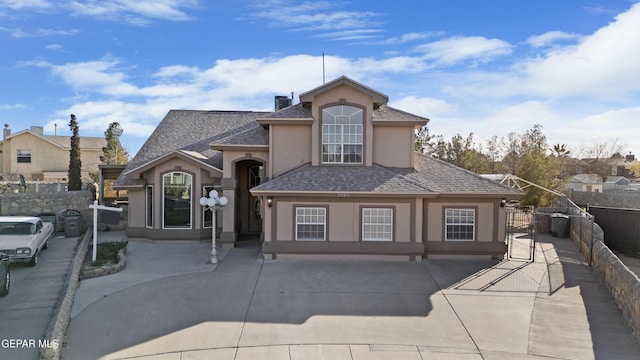 view of front of property featuring a gate, stucco siding, roof with shingles, and fence