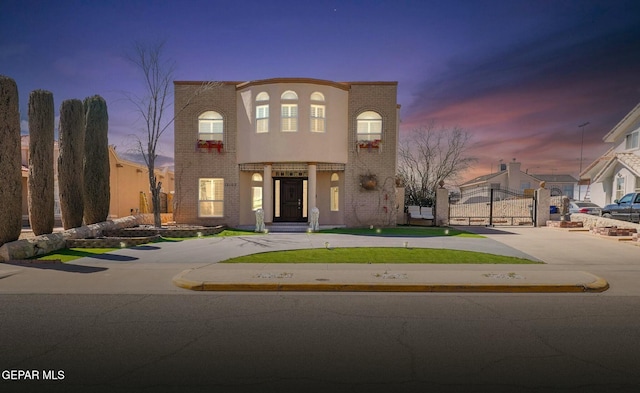 view of front of house with a gate and brick siding