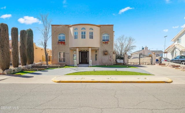 view of front facade with a gate, brick siding, and stucco siding