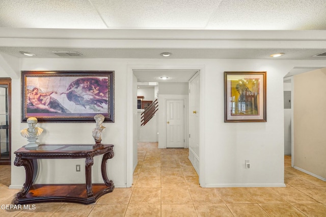 hallway featuring baseboards, stairs, visible vents, and light tile patterned flooring