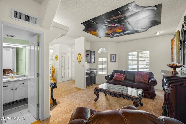 living room with visible vents, a textured ceiling, and light tile patterned flooring