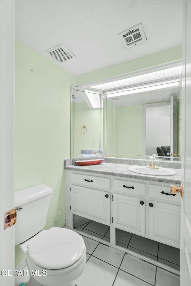 bathroom featuring toilet, vanity, and visible vents