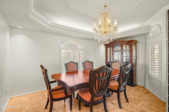 dining room with a healthy amount of sunlight, baseboards, a raised ceiling, and a textured ceiling