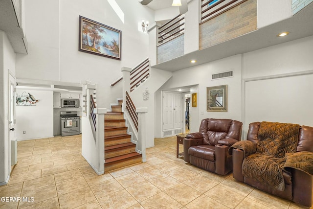 living room featuring a high ceiling, stairs, visible vents, and light tile patterned flooring