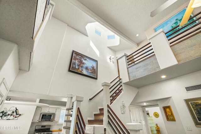 staircase with visible vents, a textured ceiling, and a high ceiling