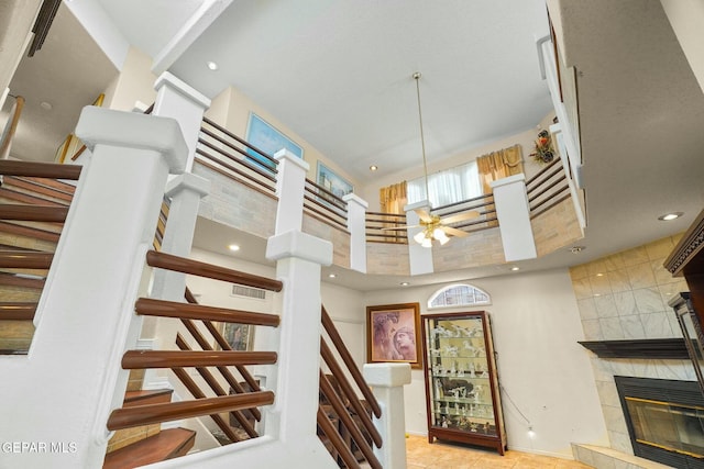 stairs featuring recessed lighting, visible vents, a high ceiling, a tiled fireplace, and tile patterned floors