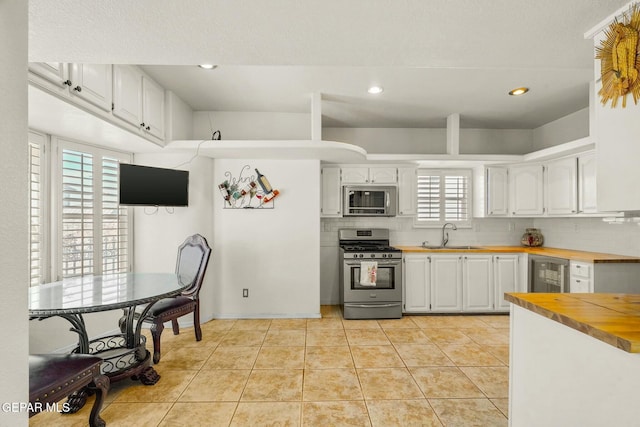 kitchen with wine cooler, light tile patterned floors, stainless steel appliances, decorative backsplash, and wood counters