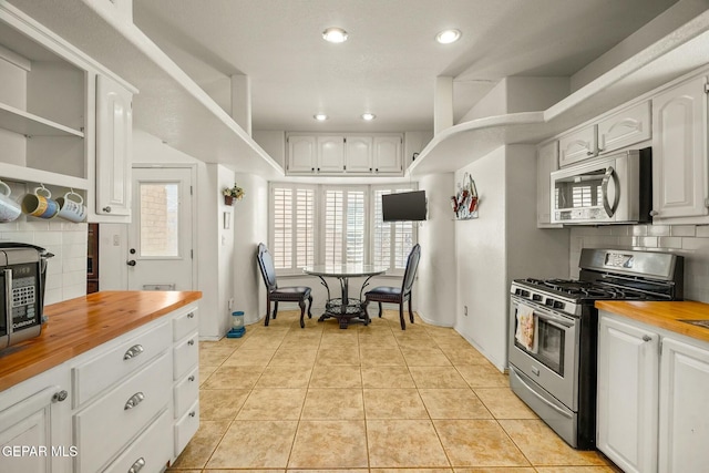 kitchen featuring butcher block countertops, white cabinetry, appliances with stainless steel finishes, and light tile patterned floors