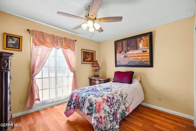 bedroom with a textured ceiling, wood finished floors, a ceiling fan, and baseboards