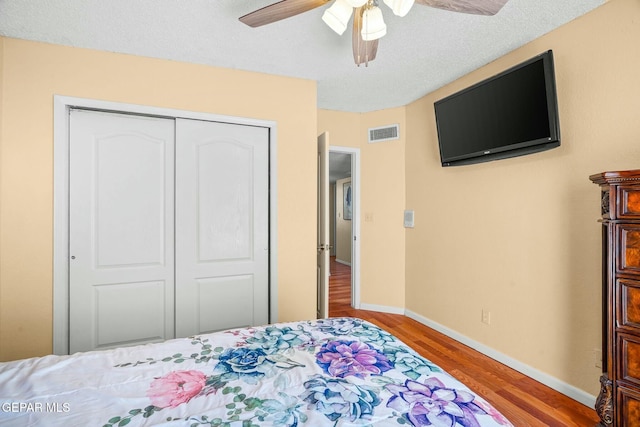 bedroom featuring a closet, visible vents, baseboards, and wood finished floors