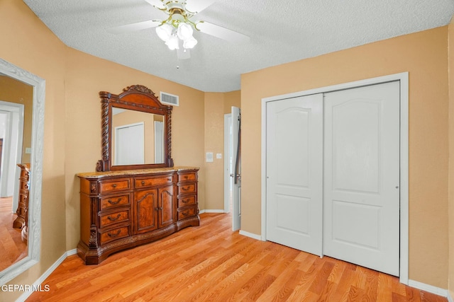 bedroom featuring a textured ceiling, a closet, visible vents, and light wood-style floors