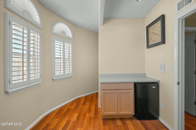 interior space featuring baseboards, light wood finished floors, visible vents, and refrigerator